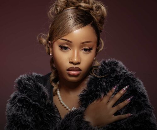 Uncle Waffles seated beside Ice Spice, NYFW front row sighting, fans react social media, visible discomfort body language, celebrity style moment, Bona Magazine