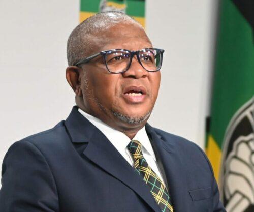 Fikile Mbalula speaking at media briefing, Pretoria courtroom building exterior, South African politics legal drama, Bona Magazine