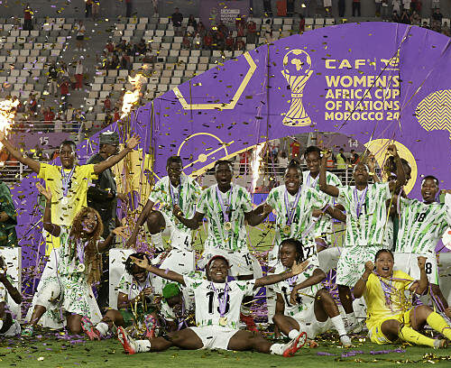 TOPSHOT - Nigeria's players celebrate with the trophy on the podium after winning the 2025 Women's Africa Cup of Nations final football match against Morocco at Prince Moulay Abdellah Stadium in Rabat on July 26, 2025. (Photo by Abdel Majid BZIOUAT / AFP) (Photo by ABDEL MAJID BZIOUAT/AFP via Getty Images)