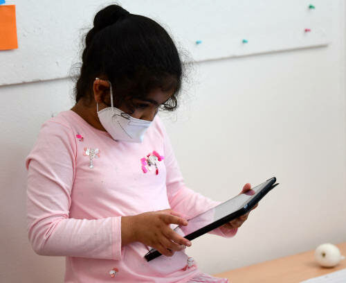 A pupil, wearing a protective face mask, works with an iPad during a summer project at the primary school 'Sonnenschule' in Beckum, western Germany, on July 6, 2021. North-Rhine Westphalia's Minister of Education and Schools visits projects that have received funding from the state programme "Extra Time for Learning" during the summer. (Photo by Ina FASSBENDER / AFP) (Photo by INA FASSBENDER/AFP via Getty Images)