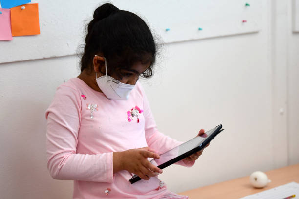 A pupil, wearing a protective face mask, works with an iPad during a summer project at the primary school 'Sonnenschule' in Beckum, western Germany, on July 6, 2021. North-Rhine Westphalia's Minister of Education and Schools visits projects that have received funding from the state programme "Extra Time for Learning" during the summer. (Photo by Ina FASSBENDER / AFP) (Photo by INA FASSBENDER/AFP via Getty Images)
