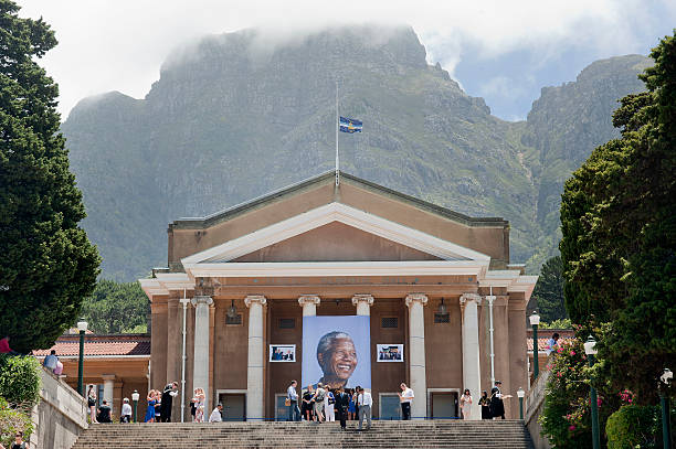 Students celebrate their graduation ceremony on the steps of Cape Town University where a giant picture of Nelson Mandela hangs down on December13 2013, in Cape Town. Mandela, South Africa's first democratically elected president, and Nobel Peace Prize winner, died at his home in Johannesburg on December 5, 2013. AFP PHOTO / RODGER BOSCH (Photo credit should read RODGER BOSCH/AFP via Getty Images)