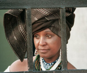 Winnie Mandela, the wife of political prisoner Nelson Mandela, looks out from behind the barred gate at her home, where she lived in defiance of a 1985 government order banishing her to the Orange Free State. (Photo by David Turnley/Corbis/VCG via Getty Images)