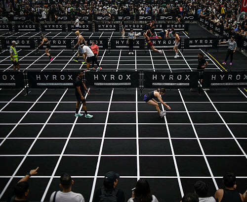 Participants compete in the "burpee broad jumps" event during the Hyrox fitness